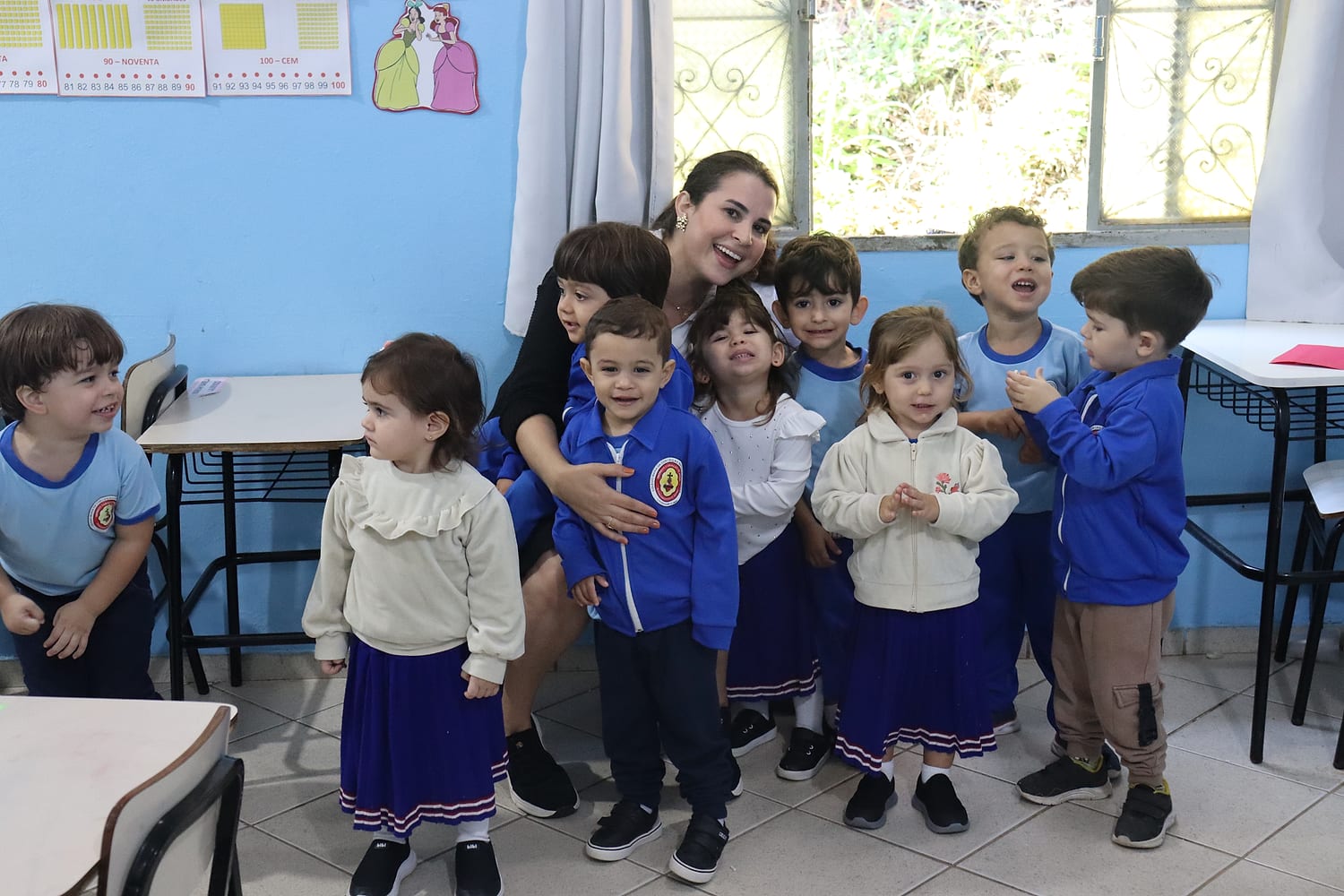 Professora abraçada às crianças da Educação Infantil na sala